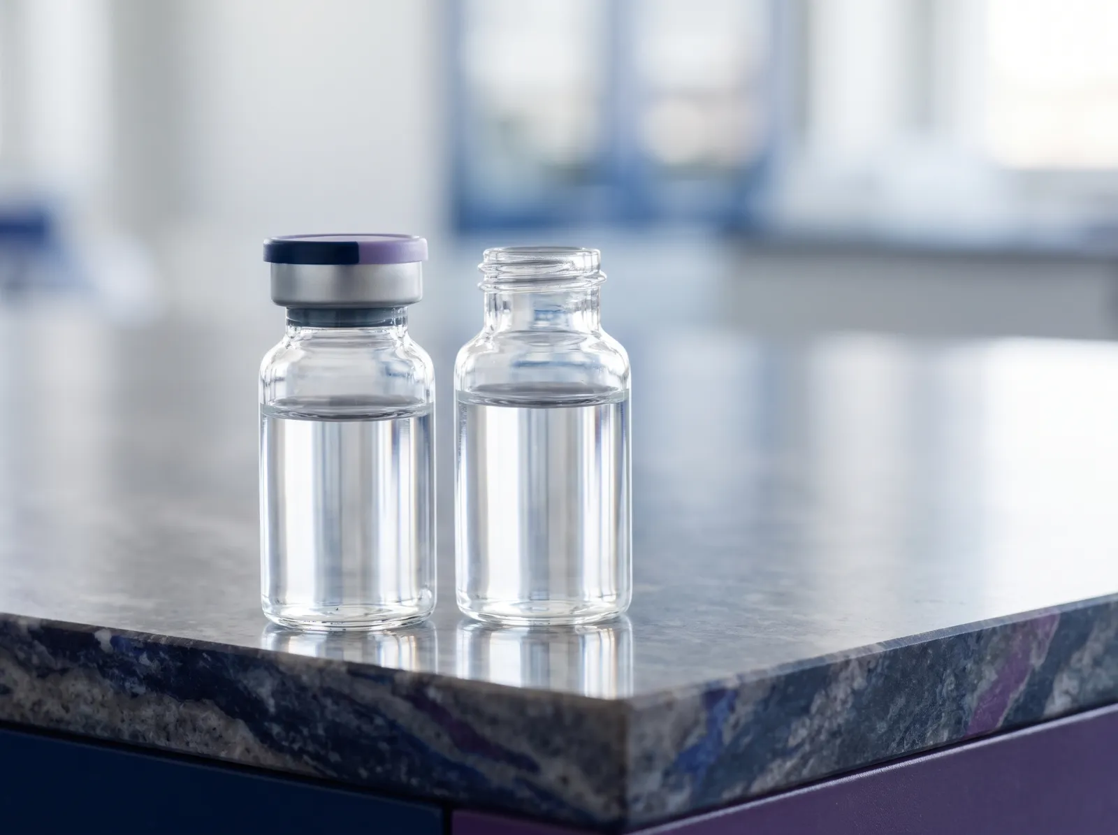 Two clear glass vials of sterile diluent side by side on a laboratory bench, one capped and one uncapped